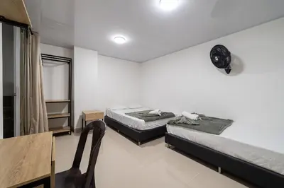 two beds in a room with a table and a chair at Hotel Doxa in Medellín