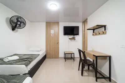 a hotel room with a bed and a desk and a tv at Hotel Doxa in Medellín