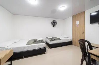 two beds in a room with a table and a desk at Hotel Doxa in Medellín
