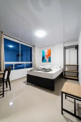 a bedroom with a bed and a large window at Hotel Doxa in Medellín
