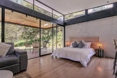 a bedroom with a bed and a couch and windows at Soy Local Reserva Sajonia in Rionegro