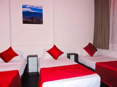 a room with three beds with red pillows at Hotel San Marcos in Manizales