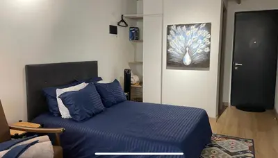 a bedroom with a bed with blue sheets and a painting at Loft con Patio privado in Medellín