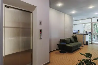 an office lobby with a elevator and a green couch at Spot Building - Apartments in Medellín