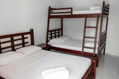 a room with two bunk beds with white sheets at Victoria Imperial Hotel in Mariquita