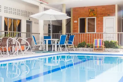 a swimming pool with chairs and an umbrella at Victoria Imperial Hotel in Mariquita
