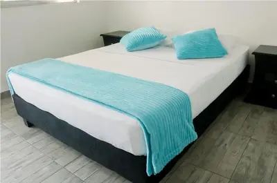 a white bed with blue pillows on top of it at Victoria Imperial Hotel in Mariquita