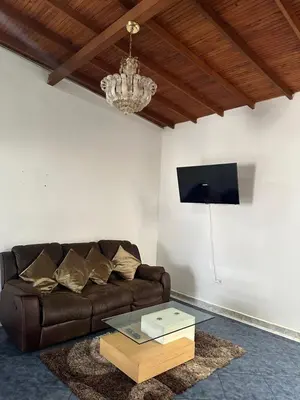 a living room with a brown couch and a chandelier at Casa grande parque central in San Rafael