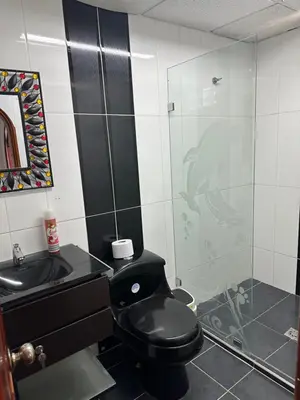 a bathroom with a black toilet and a shower at Casa grande parque central in San Rafael