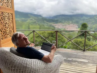 a man sitting in a wicker chair with a glass of wine at Finca Milena Jardin Antioquía in La Morelia