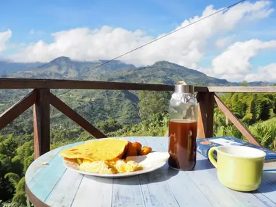 a table with a plate of food and a drink at Finca Milena Jardin Antioquía in La Morelia