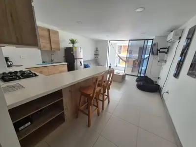 a kitchen with a counter and chairs and a refrigerator at Apartamento Luareles-San joaquin-Balcon in Medellín