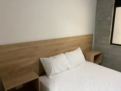 a bedroom with a white bed with a wooden headboard at Hospedaje San Diego in Medellín