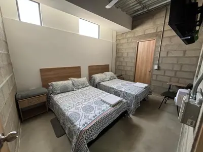 two beds in a room with two windows at Hospedaje San Diego in Medellín