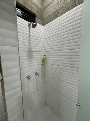 a bathroom with a shower with white tiles at Hospedaje San Diego in Medellín