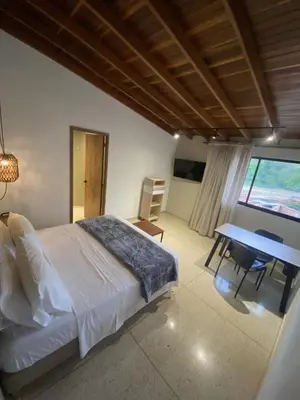 a bedroom with a bed and a desk and a table at Hotel La Vega in Concepción