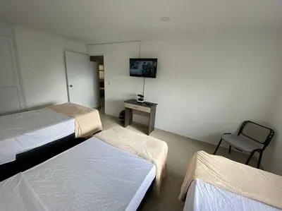a hotel room with two beds and a chair at laureles excelente ubicacion la 70 estadio, cerca al poblado in Medellín