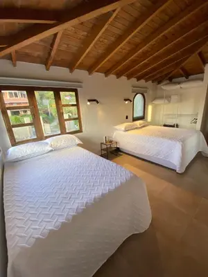 two white beds in a room with windows at Habitación con baño privado en casa de campo ubicada en Santa Elena in Santa Elena