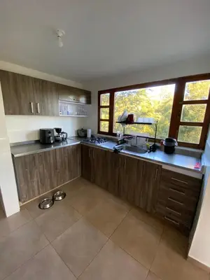 a kitchen with wooden cabinets and a large window at Habitación con baño privado en casa de campo ubicada en Santa Elena in Santa Elena
