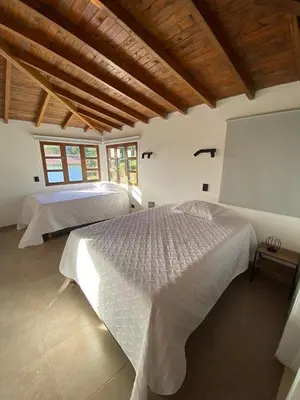 two beds in a bedroom with wooden ceilings at Habitación con baño privado en casa de campo ubicada en Santa Elena in Santa Elena