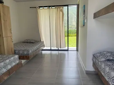 a room with two beds and a sliding glass door at Finca en sopetrán in Sopetran