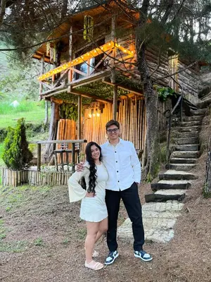 a man and a woman standing in front of a building at Refugio Natural - Cabañas Ecológicas con Jacuzzi, Guarne in Guarne