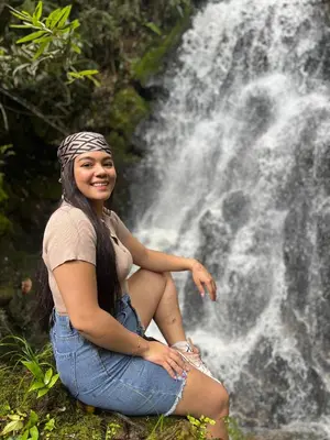 a woman sitting in front of a waterfall at Refugio Natural - Cabañas Ecológicas con Jacuzzi, Guarne in Guarne