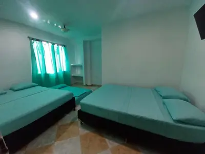 two beds in a bedroom with green sheets and a window at HotelHR in Doradal