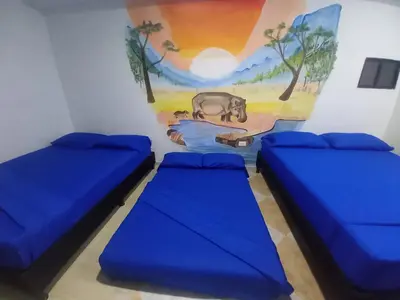 two beds in a room with a painting on the wall at HotelHR in Doradal