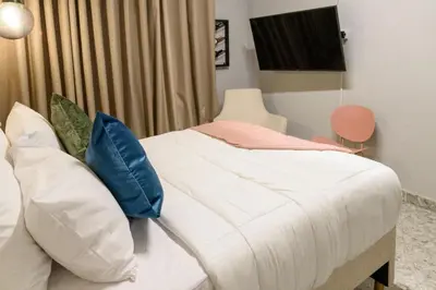 a bedroom with a white bed with blue pillows at Hotel Hola Medellín in Medellín