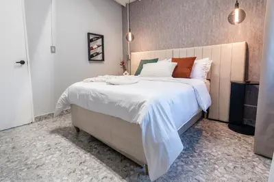 a bedroom with a large bed with white sheets at Hotel Hola Medellín in Medellín