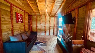 a room with a couch and a tv in a cabin at Boreal Refugio Natural in Sonsón