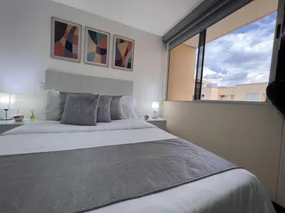 a bedroom with a large bed and a large window at Envigado Sereno in Envigado