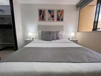 a bedroom with a large white bed with two lamps at Envigado Sereno in Envigado