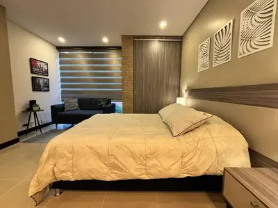 a bedroom with a large bed and a chair at Oasis elegante Poblado in Medellín