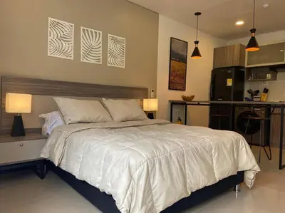 a bedroom with a large bed and a kitchen at Oasis elegante Poblado in Medellín