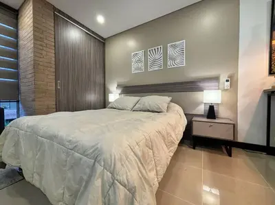 a bedroom with a large bed and a nightstand and two pictures at Oasis elegante Poblado in Medellín
