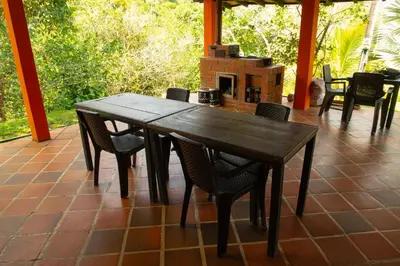 a wooden table and chairs on a patio with a fireplace at Hospedaje RioBosque San Carlos in San Carlos