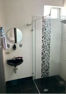 a bathroom with a sink and a glass shower at Hermosa Cabaña Familiar in San Jerónimo