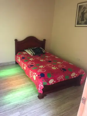 a bed with a red comforter with flowers on it at habitacion amoblada in Sonsón