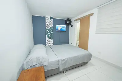 a bedroom with a bed with a blue wall at Acogedora casa cerca al estadio in Robledo