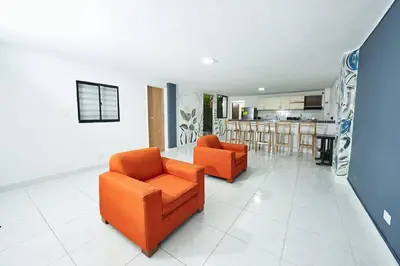 a living room with two orange chairs and a kitchen at Acogedora casa cerca al estadio in Robledo