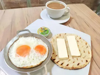 a fried egg and bread on a table with a cup of coffee at Hostal CasaBlanca, Laureles Estadio in Medellín