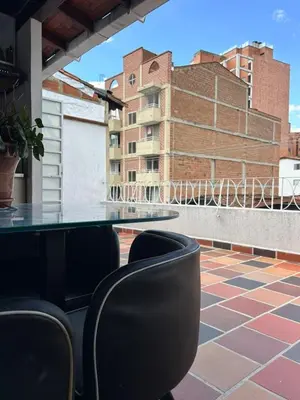 a table and chairs on a balcony with a building at Hostal CasaBlanca, Laureles Estadio in Medellín