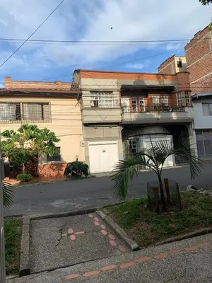a house with a palm tree in front of it at Hostal CasaBlanca, Laureles Estadio in Medellín