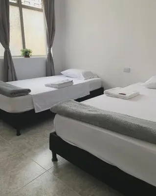 two twin beds in a room with a window at Hostal CasaBlanca, Laureles Estadio in Medellín