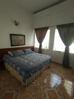 a bedroom with a bed and two windows at Hotel Bella Montaña in Manizales