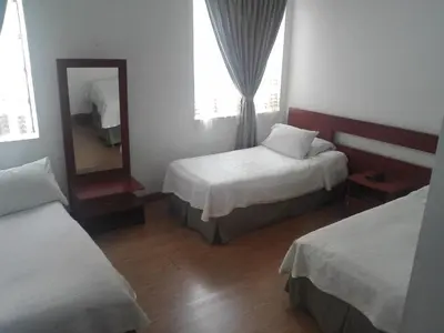 a hotel room with two beds and a mirror at Hotel Bella Montaña in Manizales