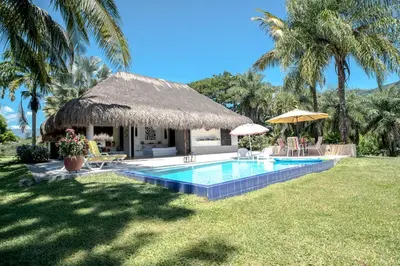 a villa with a swimming pool and a straw hut at Villa en La Pintada con Piscina in La Pintada