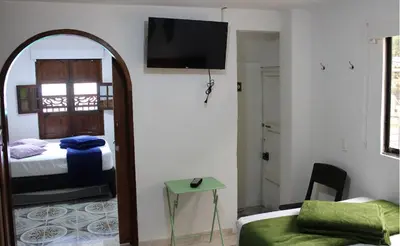 a room with a bed and a tv on a wall at Donde María Yarce Casa Turística in Jardin